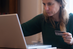 Woman looking at her laptop holding a credit card